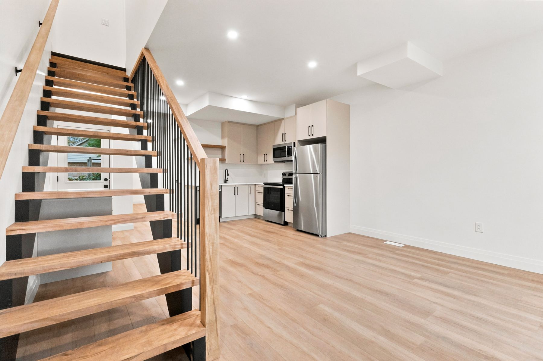 Open-concept main floor with oak staircase and kitchen at 156 Hyman St